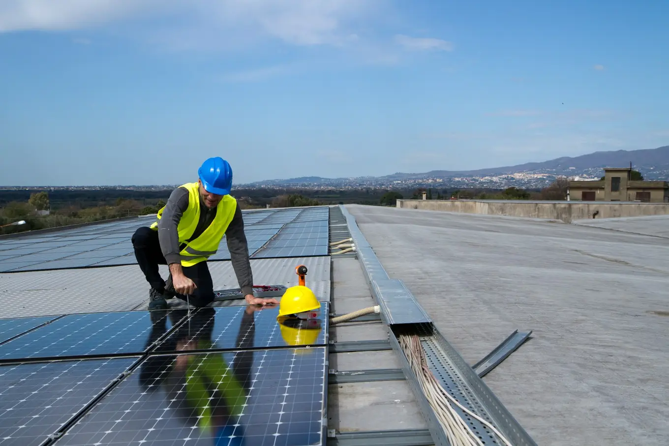 mężczyzna instaluje panele solarne na płaskim dachu